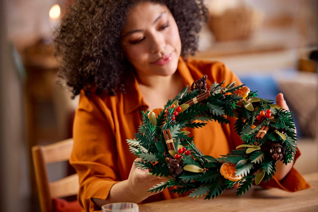 Adult builder holding the completed LEGO 10340 Wreath